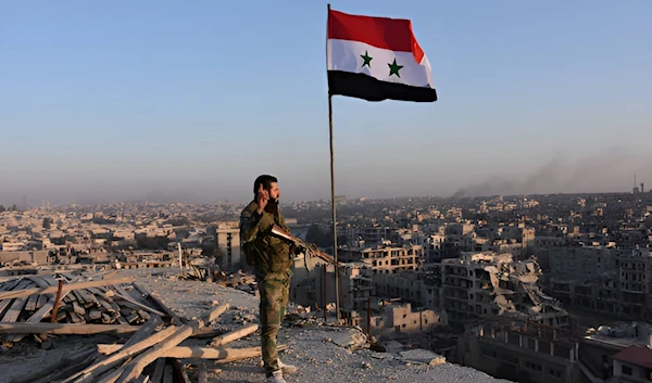 Syrian Arab Army soldier stands on top of a building overlooking Aleppo in the city's Bustan al-Basha neighbourhood on November 28, 2016 (AFP)