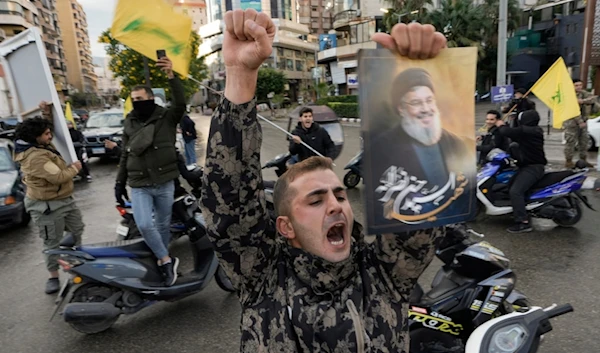 A man celebrates, carrying a picture of martyred Hezbollah leader Sayyed Hassan Nasrallah in the Southern Suburb of Beirut, Lebanon, following a ceasefire between the Israeli occupation and Hezbollah, Nov. 27, 2024 (AP)