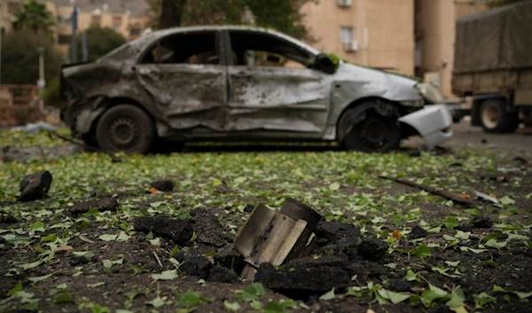 A rocket, fired from Lebanon during the hours before the start of the ceasefire, sits wedged in the ground next to a damaged car in Kiryat Shmona, northern occupied Palestine, Nov. 27, 2024. (AP)