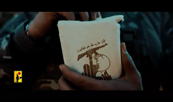 Screen grab from a Hezbollah propaganda video, showing a freedom fighter pulling out the Holy Quran from a pouch that reads the verse "Indeed, Hezbollah are the victorious ones" (Military Media)