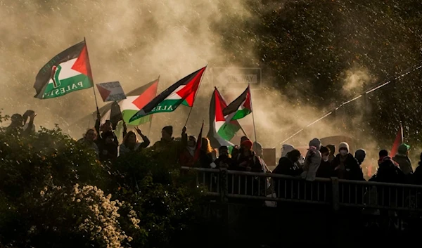 Protesters calling for a ceasefire in Gaza wave flags through smoke from a flare on an overpass as others block Interstate 5 northbound, Saturday, Jan. 6, 2024 in downtown Seattle. (AP)