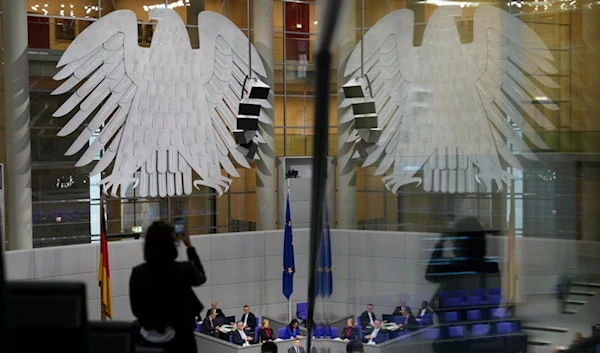 A woman at the press tribune takes a photo during a session of German parliament Bundestag in Berlin, Germany, Thursday, Nov. 7, 2024. (AP Photo/Markus Schreiber)