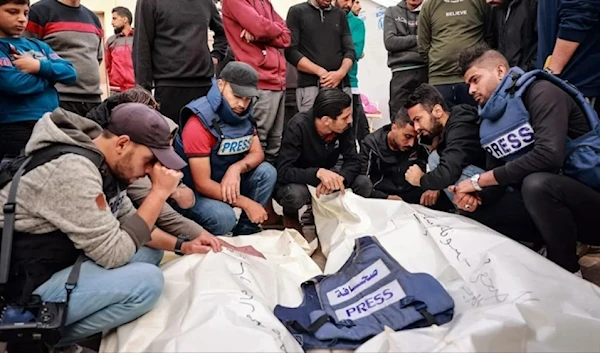 Friends and colleagues of two Palestinian journalists, Hasouna Slim and Sari Mansoor, killed in an Israeli strike, mourn over their bodies during their funeral in Deir al-Balah in southern Gaza, on November 19, 2023. (AFP)