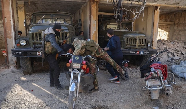 A terrorist checks a motorcycle next to abandoned army vehicles in the town of Maarat al-Numan, southwest of Aleppo, Syria, Saturday, November 30, 2024 (AP)