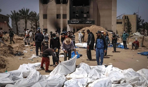 Palestinian health workers unearth a body buried by Israeli occupation forces in mass graves inside the Nasser hospital compound in Khan Younis in the southern Gaza Strip on April 21, 2024. (AFP)