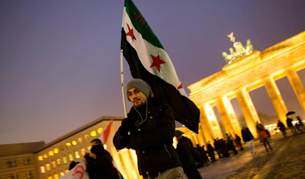 A man with a Syrian revolution flag attends a protest against the civil war in Syria and for a free Syria in front of the Brandenburg Gate in Berlin, Sunday, Dec. 23, 2012. (AP)