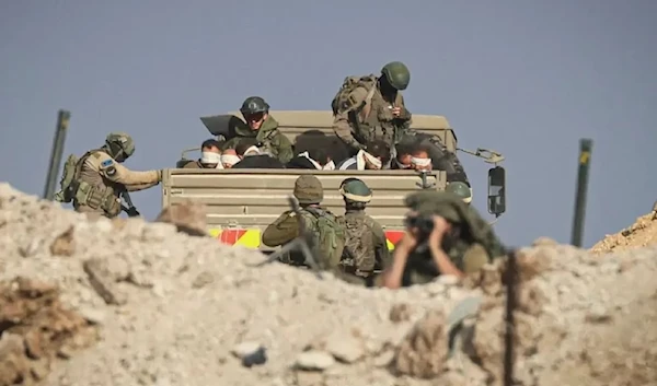 Israeli soldiers detained blindfolded Palestinian men in a military truck on a road in the Zaytun district of the southern part of the Gaza Strip on November 19, 2023 (AFP via Getty Images)