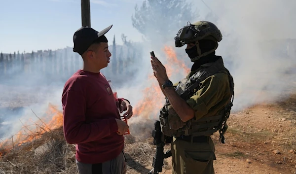 An Israeli occupation soldier checks the identification document of a Palestinian villager, in the West Bank town of Qusra, south of Nablus Tuesday, Oct. 29, 2024. (AP)