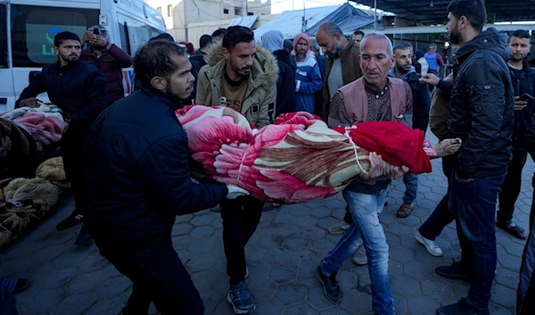 Palestinians carry the body of a relative killed in the Israeli occupation bombardment of the Gaza Strip at a hospital in Deir al-Balah, palestine, Dec. 15, 2024. (AP)