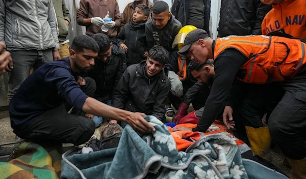 Palestinians mourn over the bodies of civil defense workers victims of an Israeli army strike in the Nuseirat camp, at the Al-Aqsa Martyrs hospital in Deir al-Balah, central Gaza Strip, Sunday Dec.16, 2024. (AP)