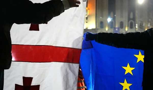 Demonstrators hold a EU, right, and Georgian flags during a protests against the government's decision to suspend negotiations on joining the European Union in Tbilisi, Georgia, Dec. 5, 2024. (AP)