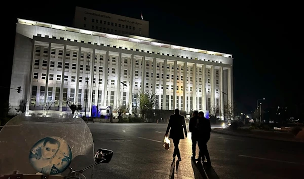 Syrian citizens walk in front the building of the Syrian Central Bank in Damascus, Syria, Saturday, December 7, 2024 (AP)