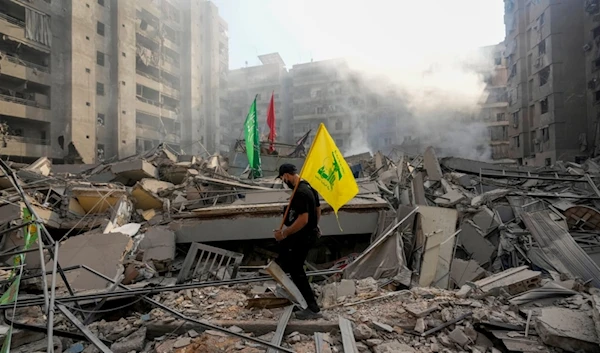 A man carries a Hezbollah flag as he walks on the rubble of his destroyed apartment following an Israeli occupation airstrike in Lebanon, Nov. 1, 2024. (AP)