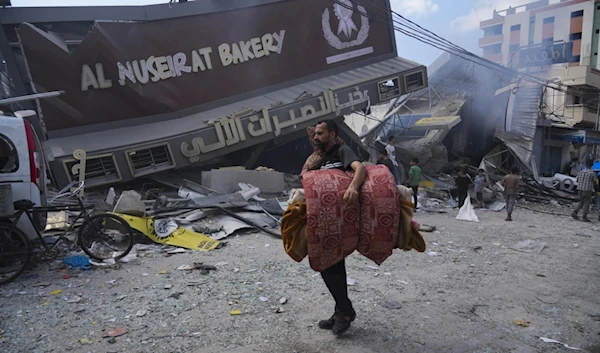 Palestinians walk past the Al Nuseirat Bakery, destroyed in an Israeli airstrike, in Nusseirat refugee camp Gaza Strip, Wednesday, Oct. 18, 2023. (AP)