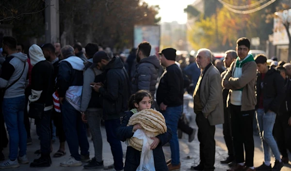 Residents stand in queue as they wait to buy bread from a bakery in the city of Aleppo, Syria, Saturday, Dec. 14, 2024. (AP Photo/Khalil Hamra)