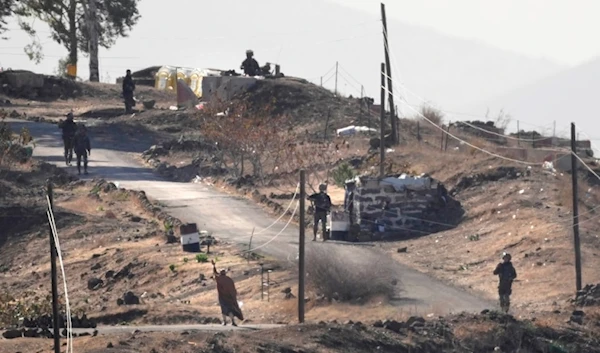 A Syrian man waves to Israeli soldiers as he approaches to negotiate with them, where they set their new position after they advanced from Golan to Maariyah village in southern Syria, Thursday, Dec. 19, 2024. (AP)