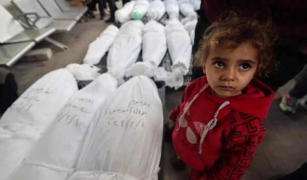 A Palestinian child stands next to the bodies of family members including children after they were killed during an Israeli airstrike on January 10, 2024, in Rafah in the Gaza Strip. (AFP)