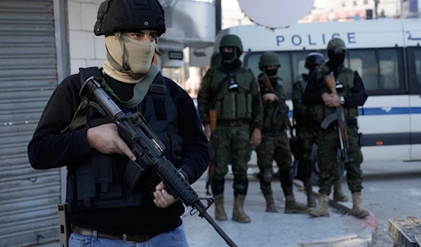 Officer from the Palestinian Authority clutches his gun as Palestinian security forces mount a major raid against Resistance factions in the Jenin camp in the occupied West Bank, Dec. 16, 2024. (AP)