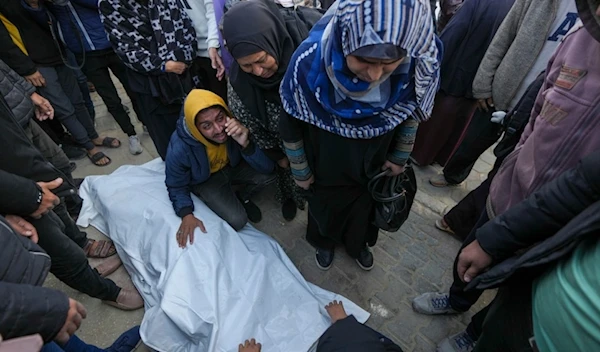 Relatives and neighbours mourn over the body of one of the victims of an Israeli strike on a home as they are prepared for the funeral outside the Al-Aqsa Martyrs Hospital in Deir al-Balah Sunday, Dec. 22, 2024. (AP)