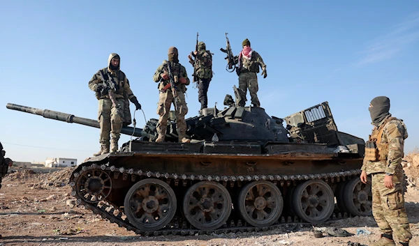 Syrian opposition fighters stand atop a seized Syrian army armoured vehicle in the outskirts of Hama, Syria, Tuesday Dec. 3, 2024. (AP