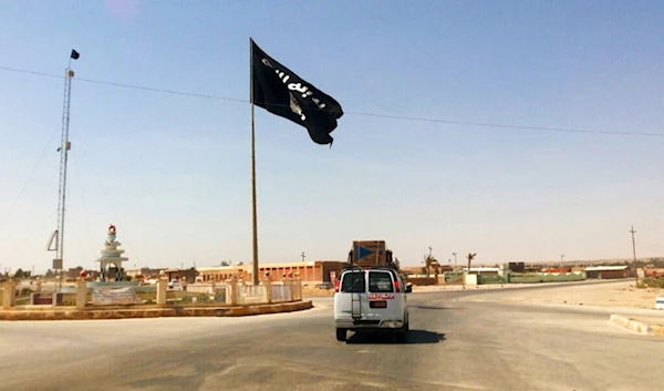 This Tuesday, July 22, 2014 photo shows a motorist passing by a flag of the Islamic State group in central Rawah, 175 miles (281 kilometers) northwest of Baghdad, Iraq. (AP)