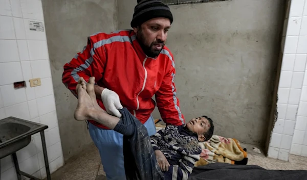 A Palestinian medic holds the body of a child killed in the Israeli bombardment of the Gaza Strip in the morgue at Al-Aqsa Hospital in Deir al-Balah, Thursday, Dec. 19, 2024. (AP)