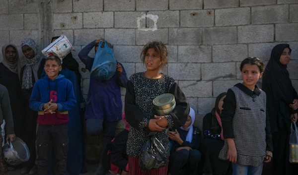 Palestinian children wait for food at a distribution center in Deir al-Balah, Gaza Strip, Tuesday, Dec. 17, 2024. (AP Photo/Abdel Kareem Hana)