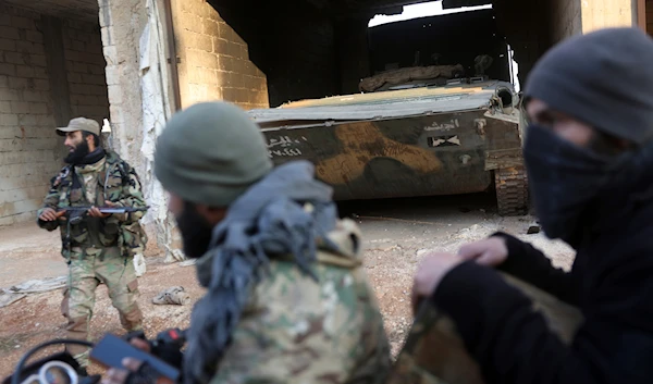 Syrian opposition fighters ride in front of a tank they allegedly captured from Syrian Government troops in Talhiya, Idlib countryside, Syria, on November 29, 2024. (AP)