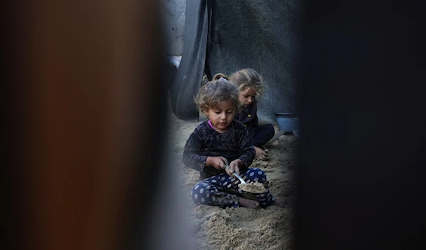 Grandchildren of Reda Abu Zarada, displaced from Jabaliya in northern Gaza, play with sand next to their tent at a camp in Khan Younis, Gaza Strip, on December 19, 2024. (AP)