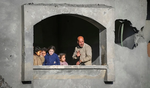 Neighbours watch the funeral procession of the victims of an Israeli occupation strike on a home in Deir al-Balah, central Gaza Strip, Palestine, amid ongoing genocide, on Dec. 22, 2024. (AP)