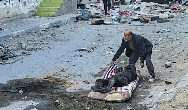 A Palestinian man uses a mattress to pull away a victim following Israeli strikes around the Kamal Adwan hospital on December 6, 2024. (AFP)