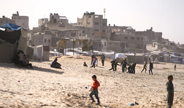 Children play on the sand in a camp for internally displaced Palestinians at the beachfront in Deir al-Balah, central Gaza Strip, Friday, Dec. 27, 2024 (AP)