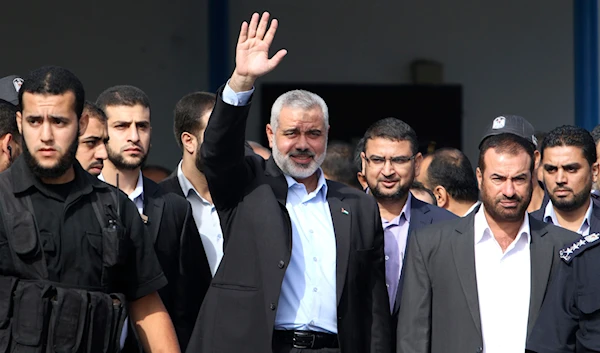 Gaza's Hamas Prime Minister Ismail Haniyeh, center, gestures at the Rafah border crossing between Egypt and Gaza, Tuesday, Oct. 18, 2011