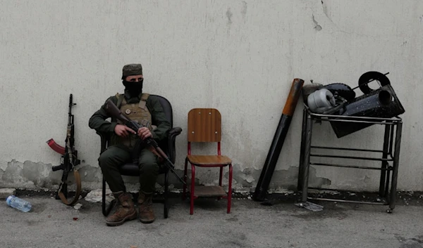 A member of the security forces of the newly formed Syrian government looks on as members of Bashar Assad's army line up to register as part of an "identification and reconciliation" process in Damascus, Syria, Dec. 30, 2024. (AP)