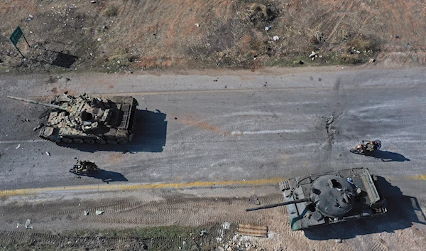 Syrian insurgents ride on motorcycles through abandoned Syrian army vehicles on a road in the outskirts of Hama, Syria, on December 3, 2024.(AP)