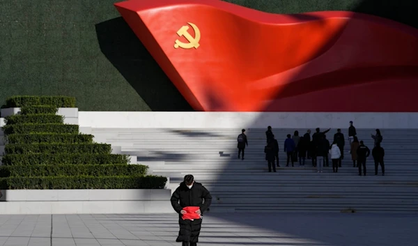 FILE - A worker folds a flag near a giant sculpture of the Chinese Communist Party flag outside the Museum of the Communist Party of China, in Beijing, Nov. 12, 2021. (AP)