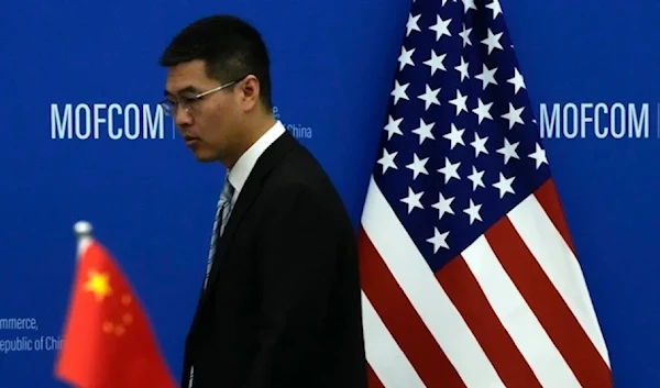 A chinese official walks by the China and US national flags at the Ministry of Commerce in Beijing on August 28,2023. (AP)