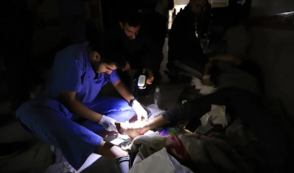 Palestinian medics treat a wounded person using torchlights at the Indonesian hospital in Beit Lahiya during the Israeli bombardment of the northern Gaza Strip, occupied Palestine, Nov. 19, 2023. (AP)