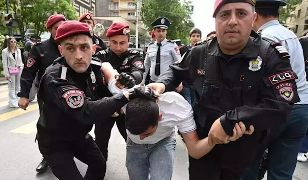 Armenian law enforcement officers detain a demonstrator in a protest against land transfer to Azerbaijan, in Yerevan, Armenia, on May 13, 2024. (AFP)