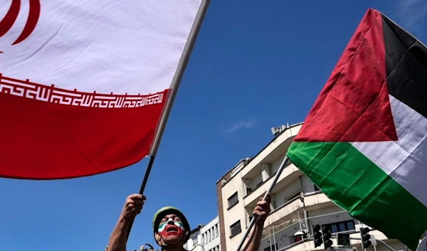 Man waves Iranian and Palestinian flags in the annual rally to mark Quds Day, in support of Palestinians, in Tehran, Iran, Friday, April 5, 2024 (AP)