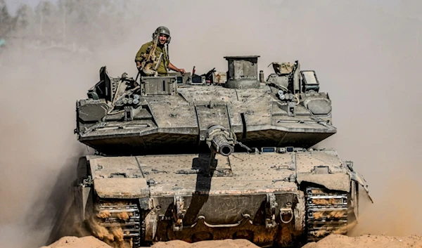 Israeli soldiers drive a tank at a staging ground near the separation line with the Gaza Strip, in southern occupied Palestine, Sunday, May 5, 2024. (AP Photo/Tsafrir Abayov)