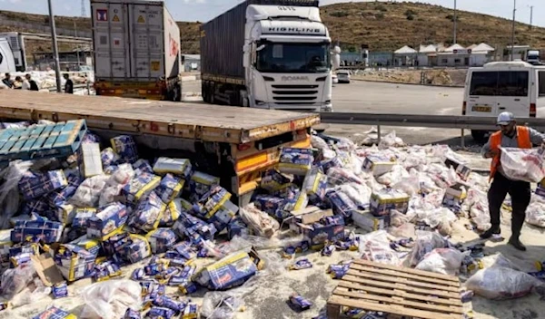 A worker clears piles of spilled food parcels scattered across the ground in a lorry park after Israeli settlers attacked Gaza aid trucks. (AFP/Getty Images)