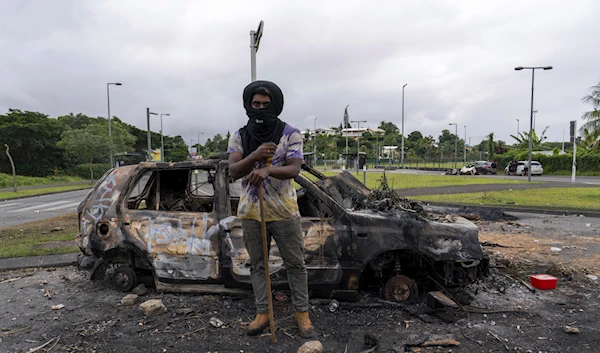 A man stands in front a burnt car after unrest in Noumea, New Caledonia, Wednesday May 15, 2024. (AP)