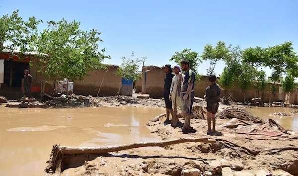 People stand near damaged homes after heavy flooding in Baghlan province, in northern Afghanistan, Sunday, May 12, 2024. (AP)