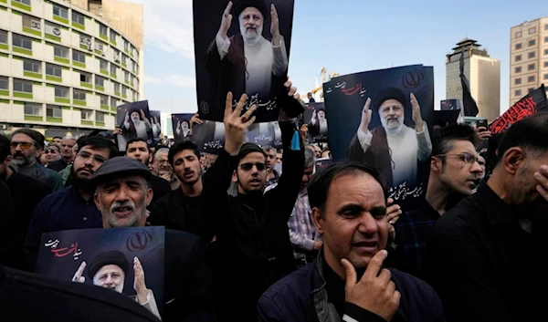 People hold up posters of Iranian President Ebrahim Raisi during a mourning ceremony for him at Vali-e-Asr square in downtown Tehran, Iran, Monday, May 20, 2024. (AP)