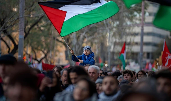 A boy waves a Palestinian flag as demonstrators march during a protest in support of Palestinians and calling for an immediate ceasefire in Gaza, in Barcelona, Spain, on Jan. 20, 2024.(AP)