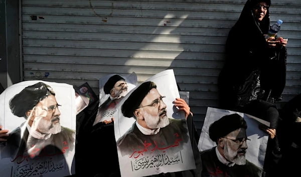 Mourners hold posters of the late Iranian President Ebrahim Raisi during a funeral ceremony for him and his companions, in Tehran, Iran, Wednesday, May 22, 2024 (AP)