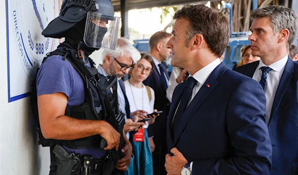 French President Emmanuel Macron talks to a policeman upon his arrival at the central police station in Noumea, New Caledonia, Thursday, May 23, 2024.(AP)