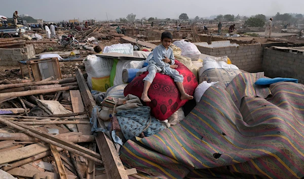 An Afghan boy sits over his family's belongings retrieved from their damaged mud homes demolished by authorities on the outskirts of Islamabad, Pakistan, Wednesday, Nov. 1, 2023. (AP)