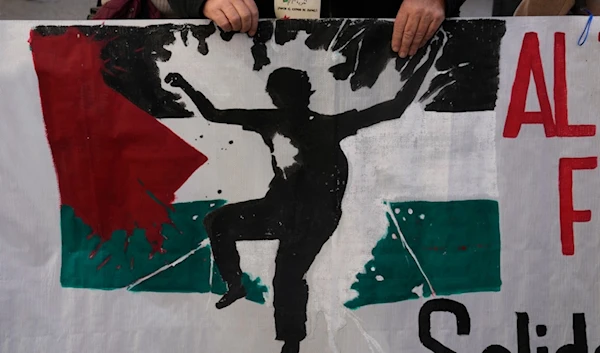 A protester takes part in a demonstration march carrying a banner showing the Palestinian flag, in support of Palestinians in Madrid, Spain, Saturday, Dec. 2, 2023. (AP)